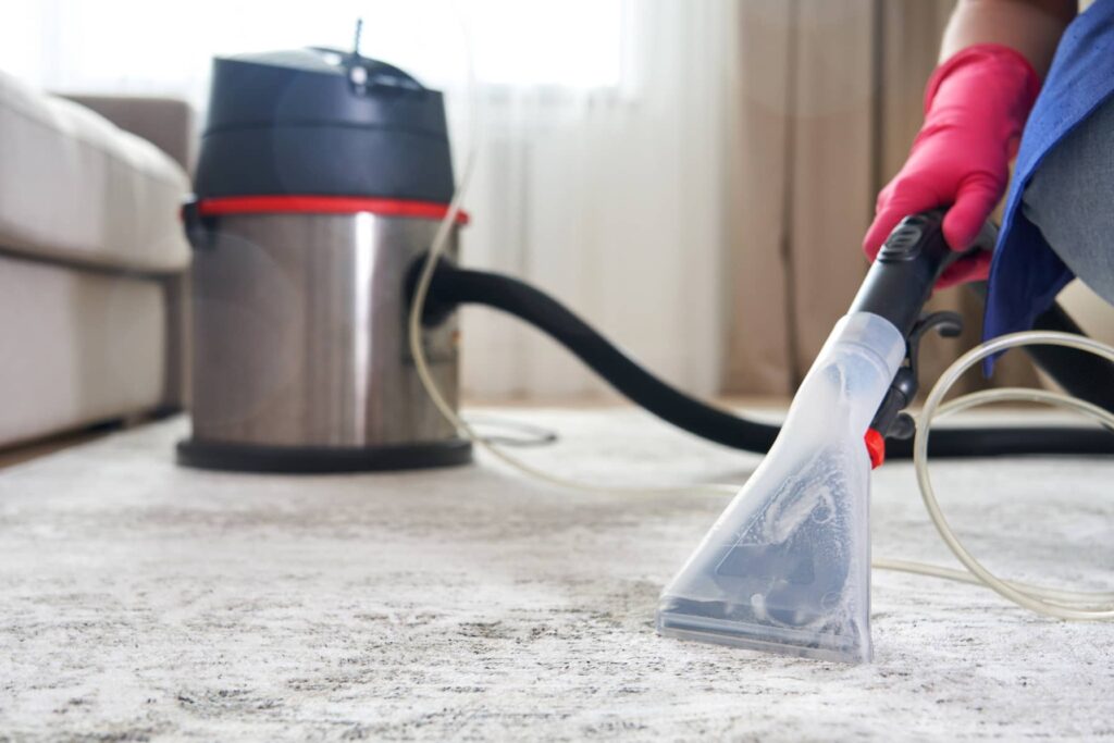 Using a traditional vacuum to get up the dry pieces of carpet and dirt.